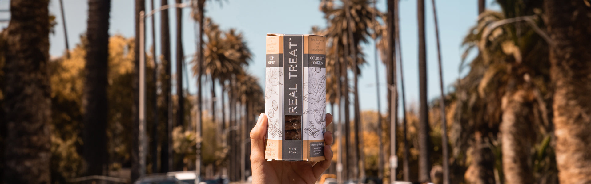 A package of Real Treat Dark Chocolate chunk with Smoked Pecans cookies is held up in the middle of Sunset Boulevard in Las Angeles.
