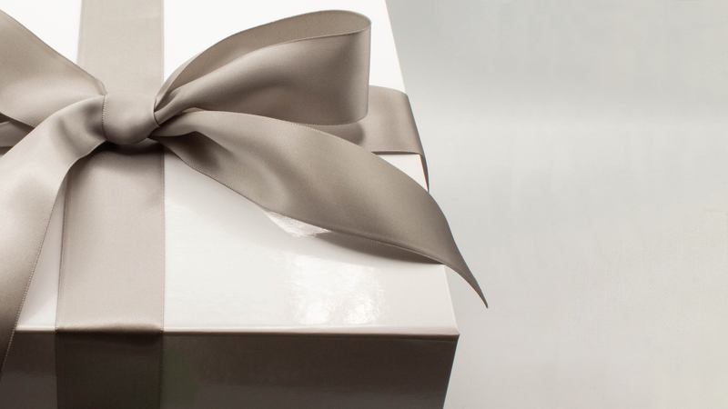 A glossy white box is tied with a silver satin ribbon