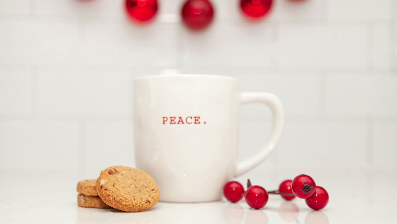 A stack of Real Treat Spiced Pecan Shortbread rests next to a white mug that reads "Peace" on it.