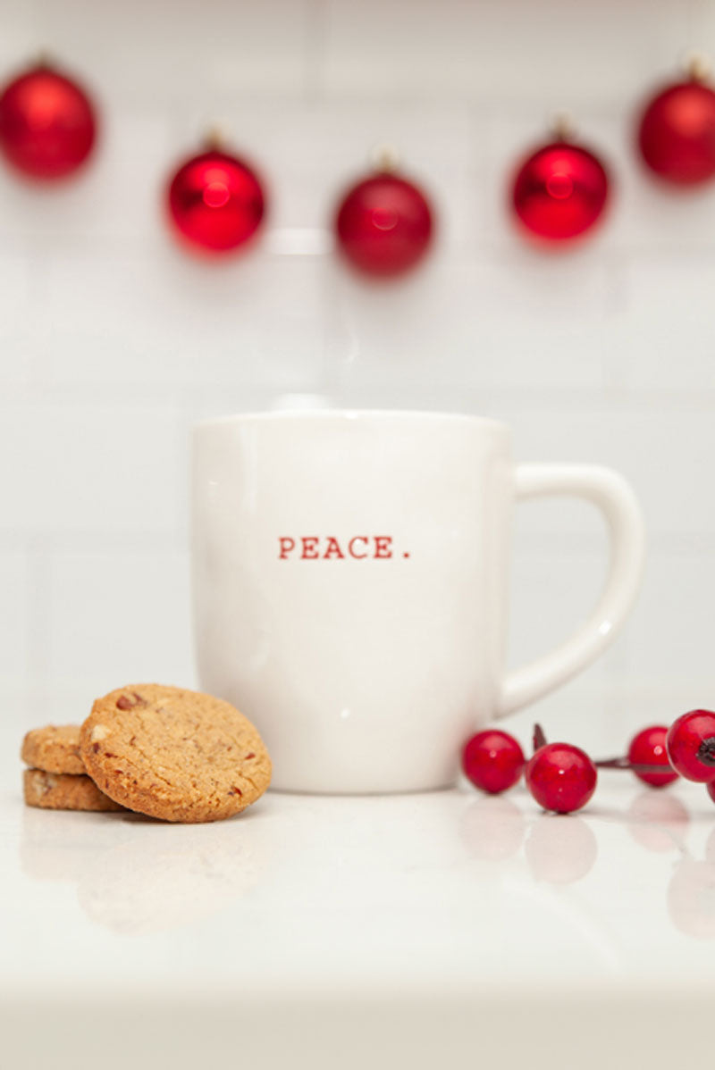 A stack of Real Treat Spiced Pecan Shortbread rests next to a white mug that reads "Peace" on it.