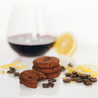 A stack of Double Dark Chocolate with a Twist with a glass of red wine and a scattering of lemon zest and dark chocolate
