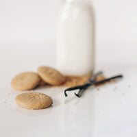 Real Treat Pantry Brown Sugar Shortbread cookies on a table with vanilla beans, sugar, and a jug of milk.