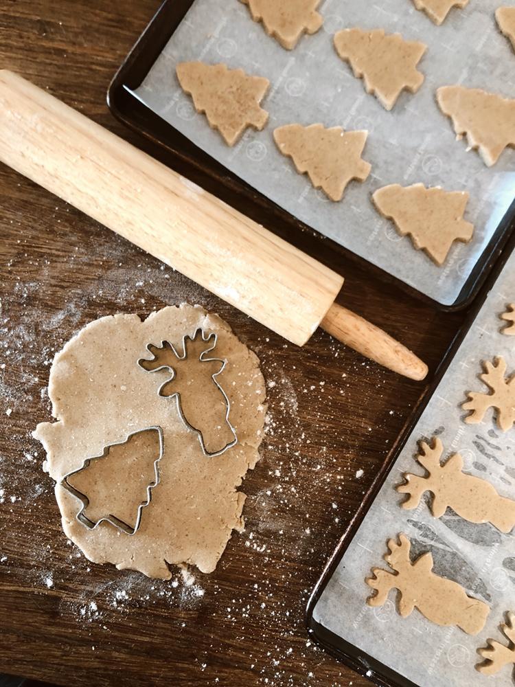 raw cookie dough is rolled on a counter with cookie cutters and a rolling pin