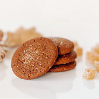 A stack of Limited Edition Real Treat Holiday Ginger Cookies next to fresh and candied ginger